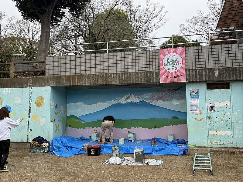 銭湯絵師の中島盛夫さんが溜池公園の壁に富士山を描いている最中に周囲の桜を見て、即興で桜を描く