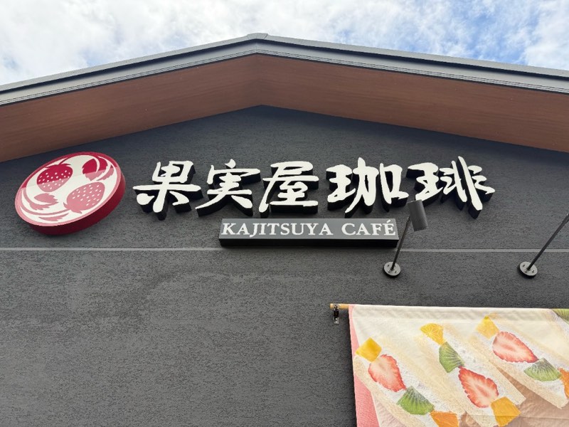 果実屋珈琲 八王子南大沢店の壁面に掲げられた店名ロゴとフルーツ柄のれん