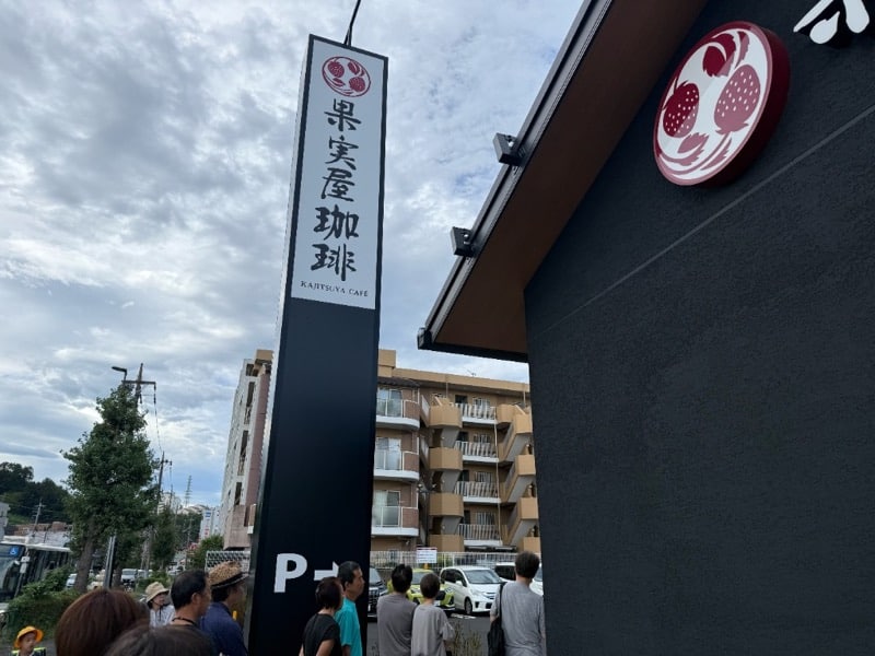 果実屋珈琲 八王子南大沢店の縦看板と開店を待つ来店客の行列