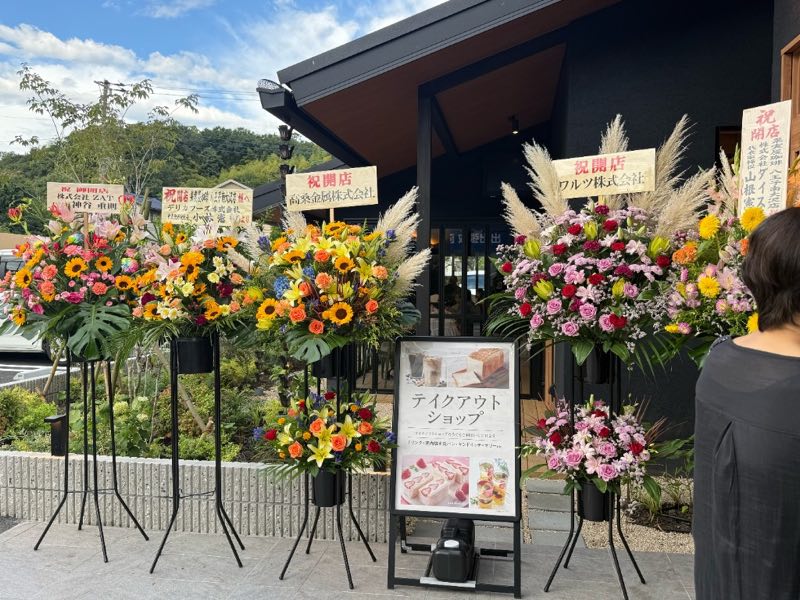 果実屋珈琲 八王子南大沢店の店頭に並ぶ開店祝いのスタンド花とテイクアウトショップの案内看板