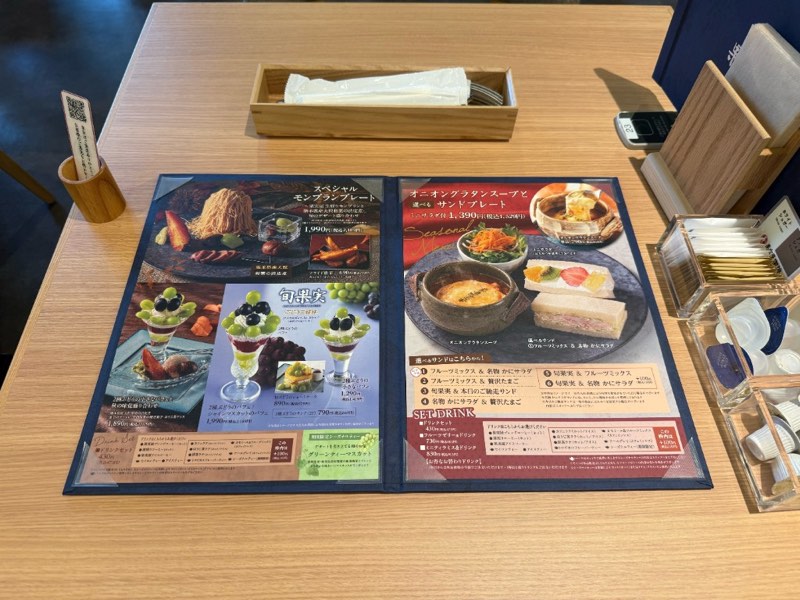 果実屋珈琲 八王子南大沢店のテーブルに置かれたスペシャルモンブランプレートと旬果実のパフェが載る旬のメニュー