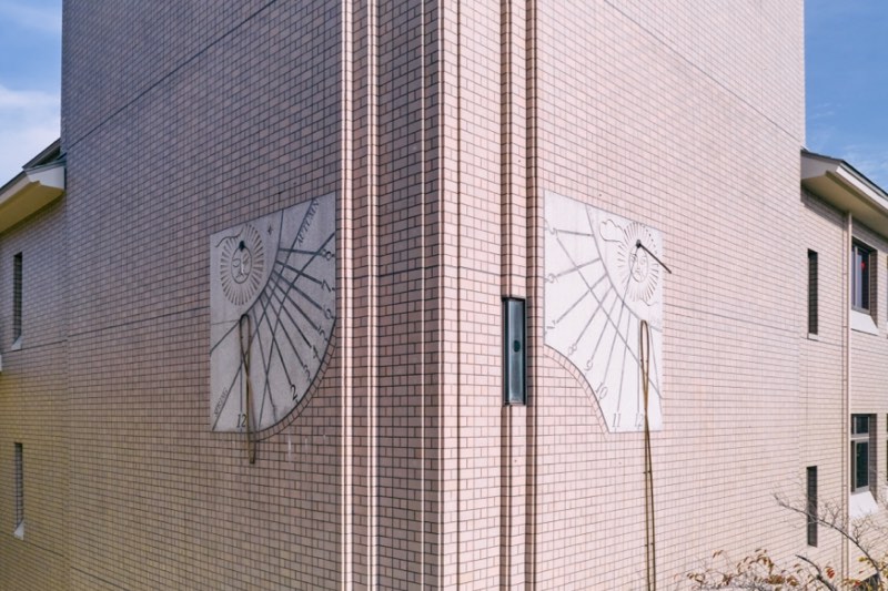 東京都立大学南大沢キャンパス・光の塔の外壁東南面と南西面に掲げられた日時計「陽刻」。南大沢で太陽が真南に来るときを正午とする