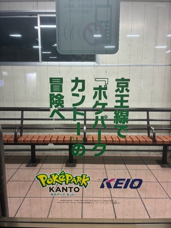 待合室ガラスに縦書きされた「京王線で『ポケパーク カントー』の冒険へ」の文言と、POKÉPARK KANTŌおよびKEIOのロゴ。奥には待合室のベンチが見える