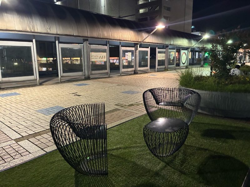 八王子市南大沢事務所前の人工芝。黒い網状の椅子2脚と丸テーブルが置かれている