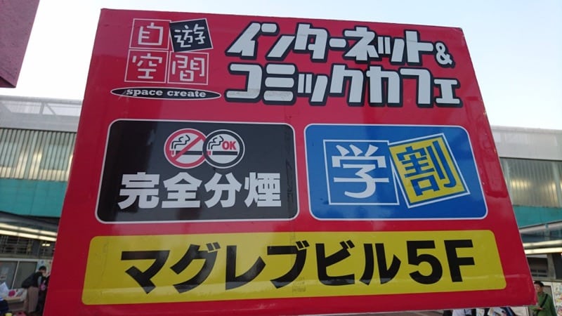 自遊空間多摩センター店の赤い立て看板。「インターネット&コミックカフェ」「完全分煙」「学割」「マグレブビル5F」と表示されている