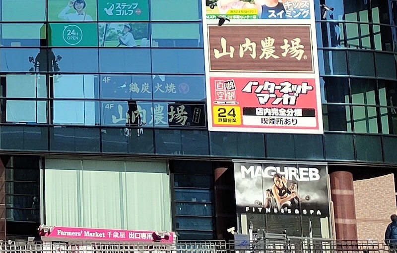 マグレブビルの看板を拡大した様子。山内農場の下に自遊空間の「インターネット マンガ」「24時間営業」「店内完全分煙」の看板が並ぶ