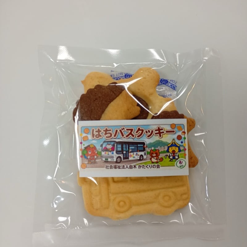 袋入りのはちバスクッキー。ラベルに商品名と由木かたくりの会、はちバスとうじてるくんのイラスト