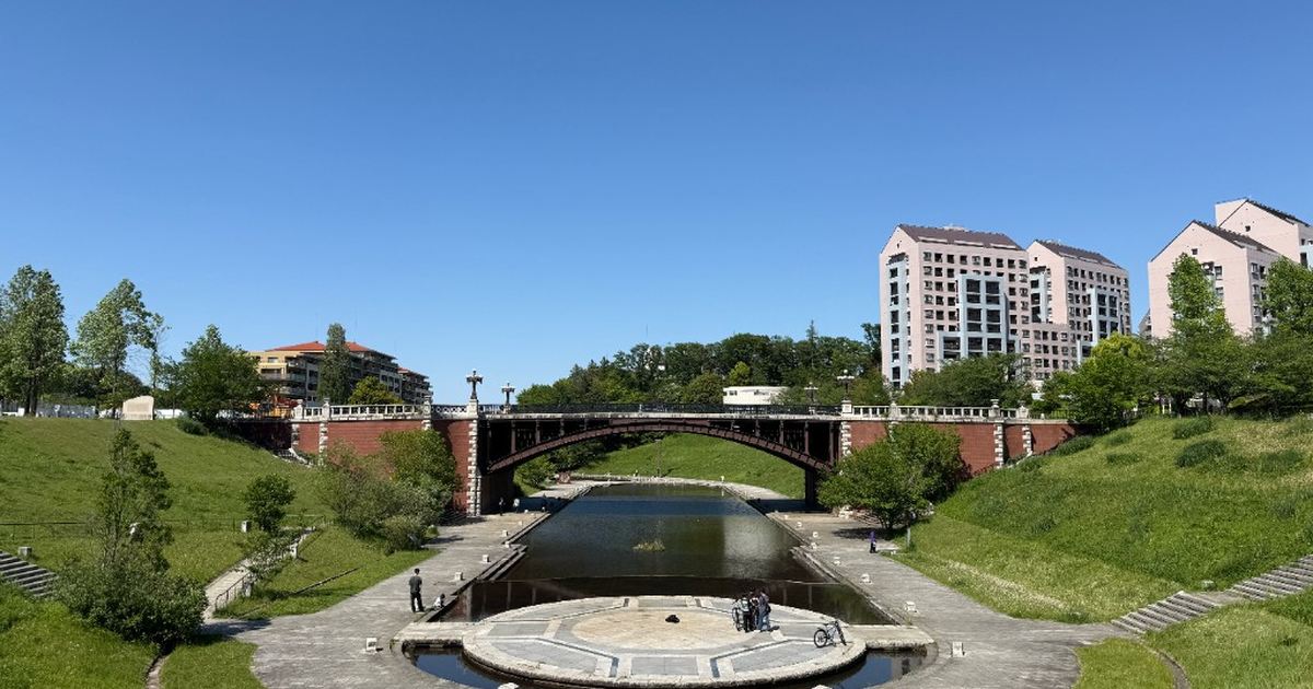 長池公園の長池見附橋。煉瓦のアーチ橋が水路をまたぎ、手前に円形のステージがある