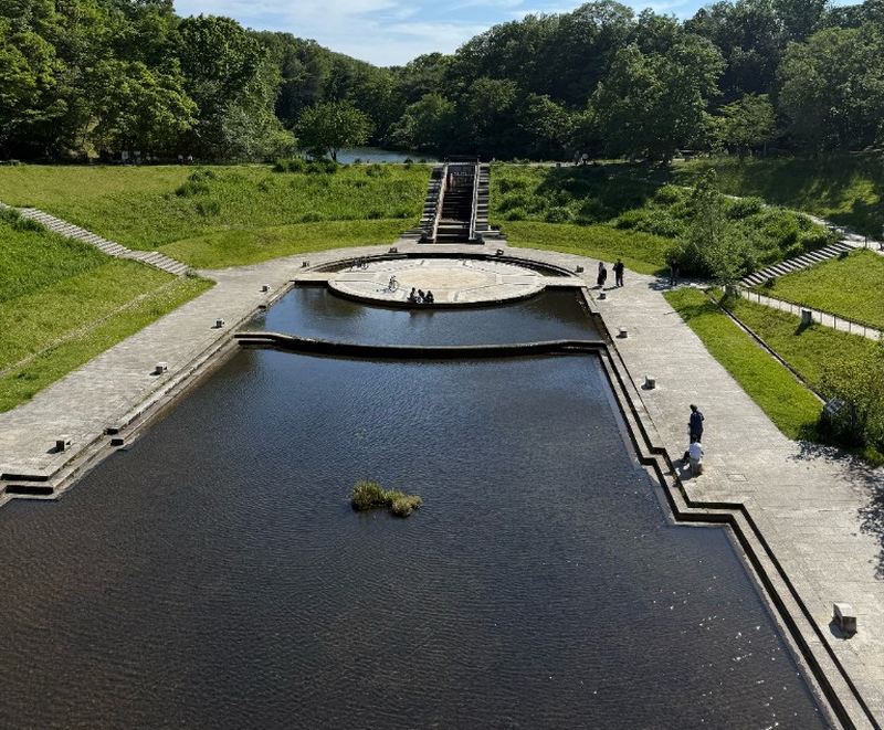 長池公園の姿池。円形のステージと水路、奥に緑の斜面がある