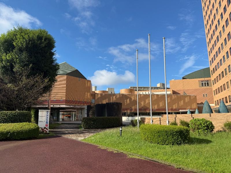 南大沢文化会館の入口。茶色のタイル外壁と円筒形の屋根、手前に赤い舗装の道がある