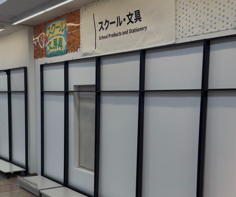 スクール・文具の表示がある白い壁と、商品のない棚