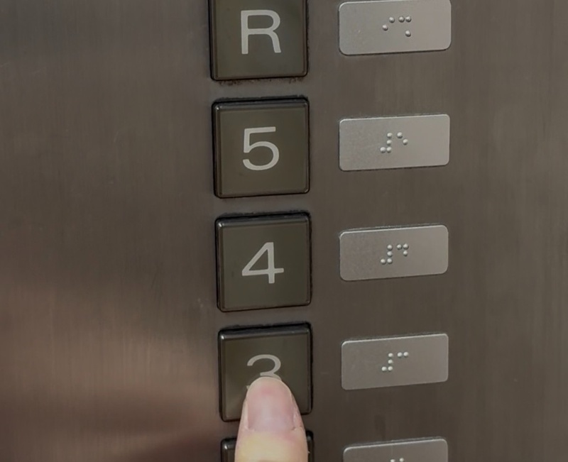 エレベーターのかご内。3階ボタンに指を添え、2〜5階のボタン