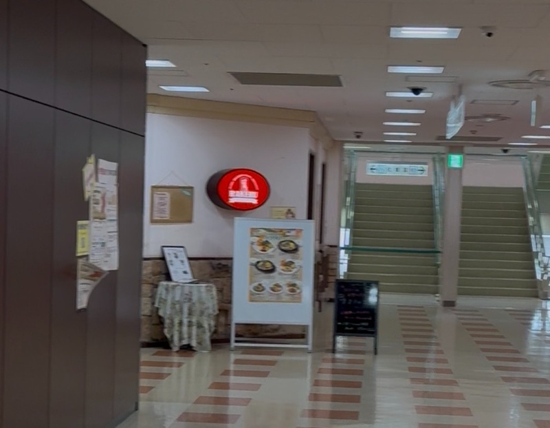 5階のラケル。赤い丸い看板と料理の案内、奥にエスカレーター