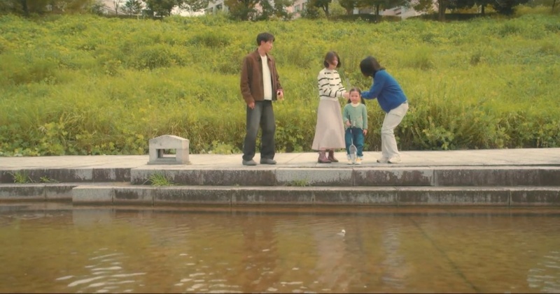 姿池の石段の上で、津倉と紗奈、女の子と母親が池に浮かぶシャトルを見つめるシーン