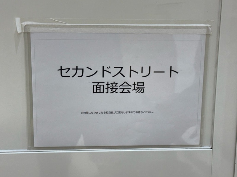 セカンドストリート面接会場と書かれた貼り紙。お時間になりましたら担当者がご案内しますのでお待ちください