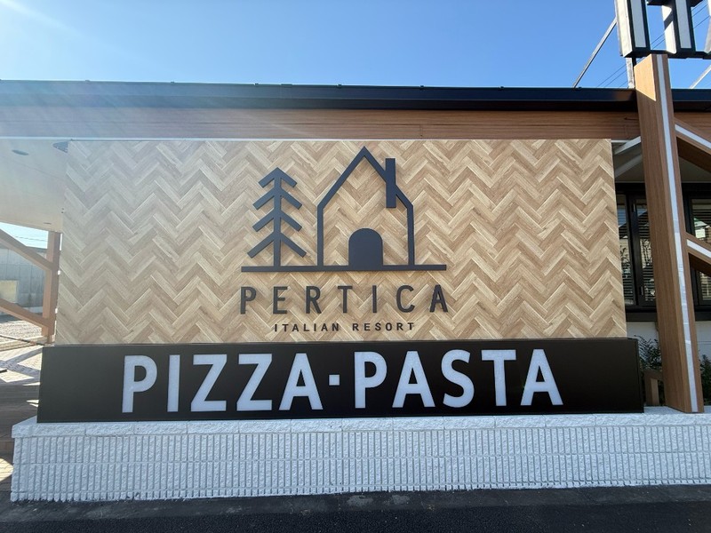 ヘリンボーン柄の壁にPERTICA ITALIAN RESORTのロゴとPIZZA・PASTAの看板
